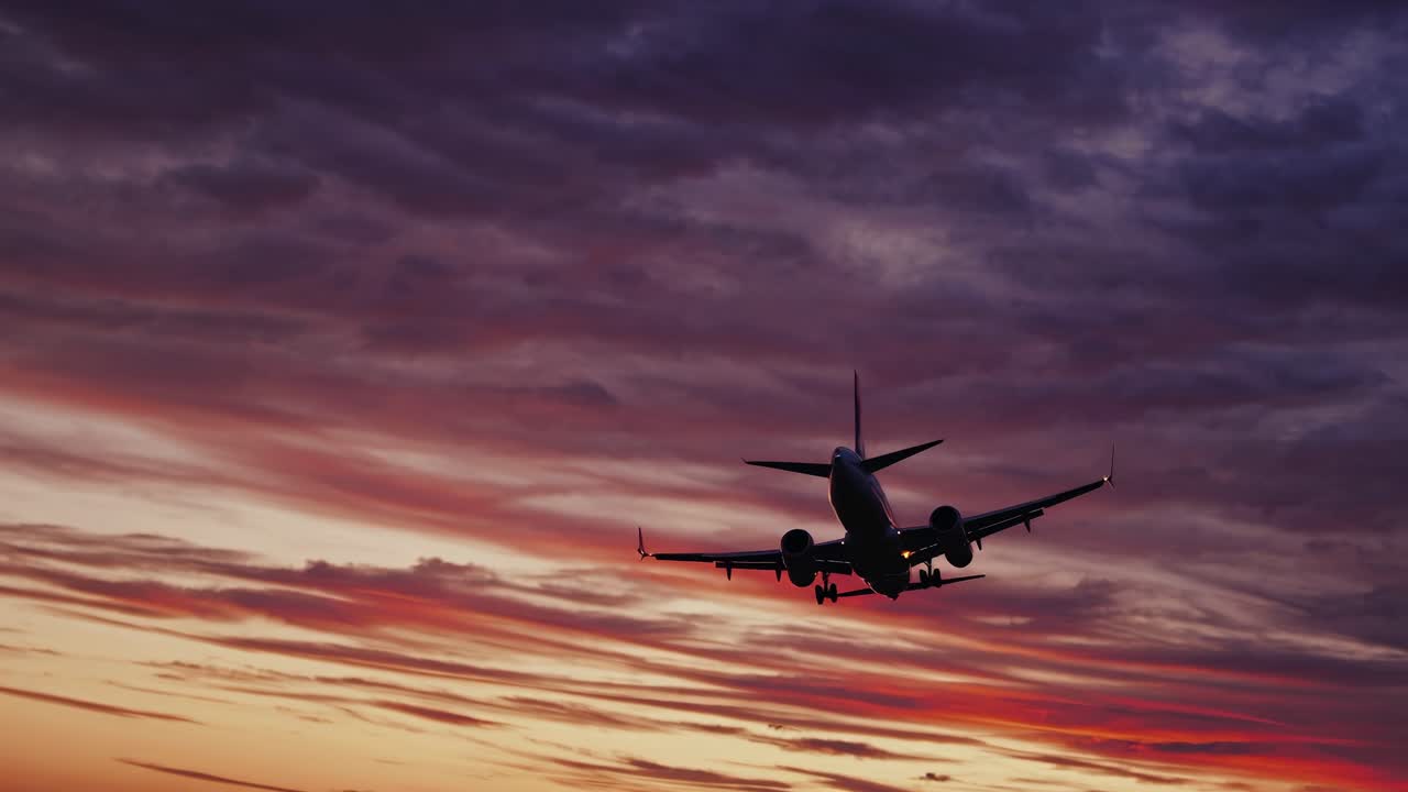 A dramatic low-angle shot of an airplane silhouetted against a vibrant sunset sky