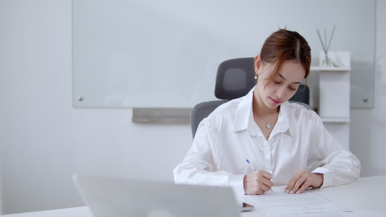 集中したプロフェッショナルが 明るいオフィスでメモを取って 創造性への献身を示しています