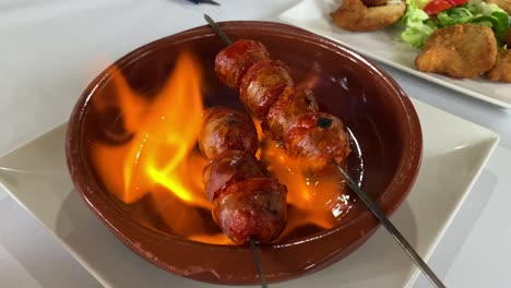 close view of a flaming chorizo in a ceramic pot in spain