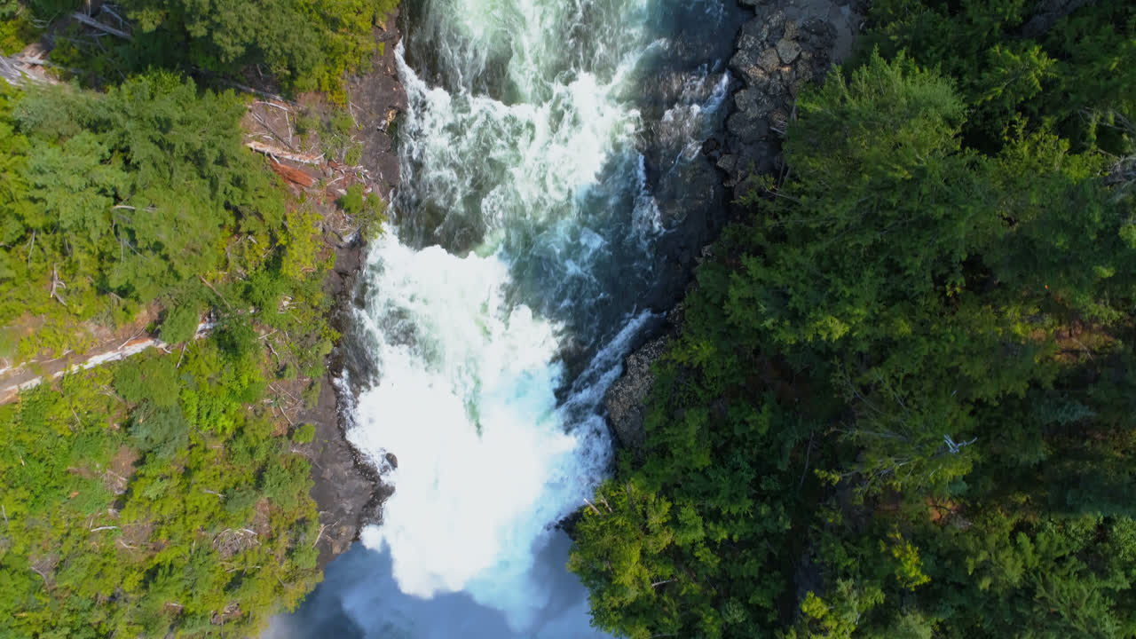 hermosa caída de agua a través del acantilado del bosque en un día soleado 4k