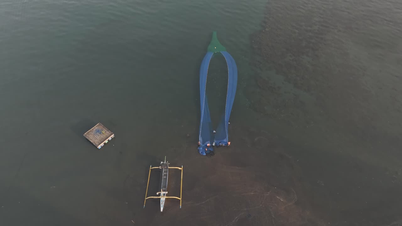 High view of net and people near calm shoreline in Indonesia