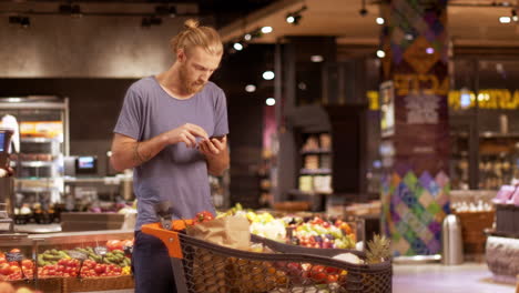 caucasian young man checking product list on smartphone in a supermarket