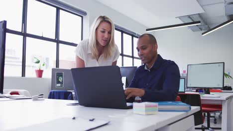 diversos colegas de negocios hablando en el escritorio usando una computadora portátil en la oficina