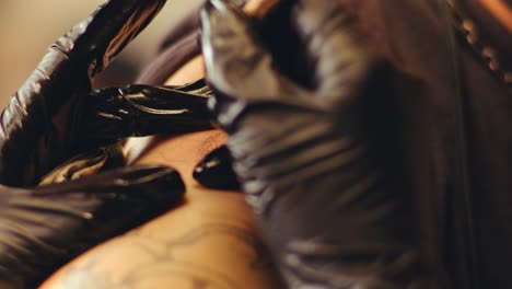 hands of tattoo master injecting ink pigment into contour drawn on skin