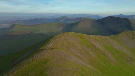 High-over-rounded-fell-summit-with-mountain-range-behind-at-golden-hour