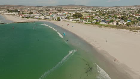 Drone-shot-of-a-kitesurfer-during-mid-day,-in-the-background-the-town-of-Langebaan