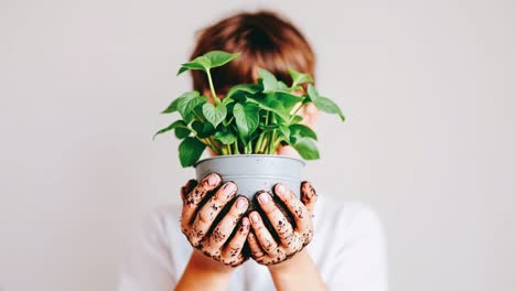 child holding a small plant in a pot