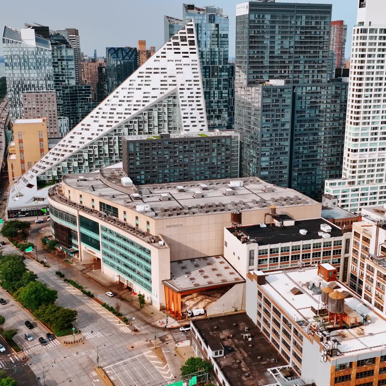 Triangle white building standing out in the architecture of New York Midtown. Drone footage above the houses and highway with heavy traffic at the waterfront