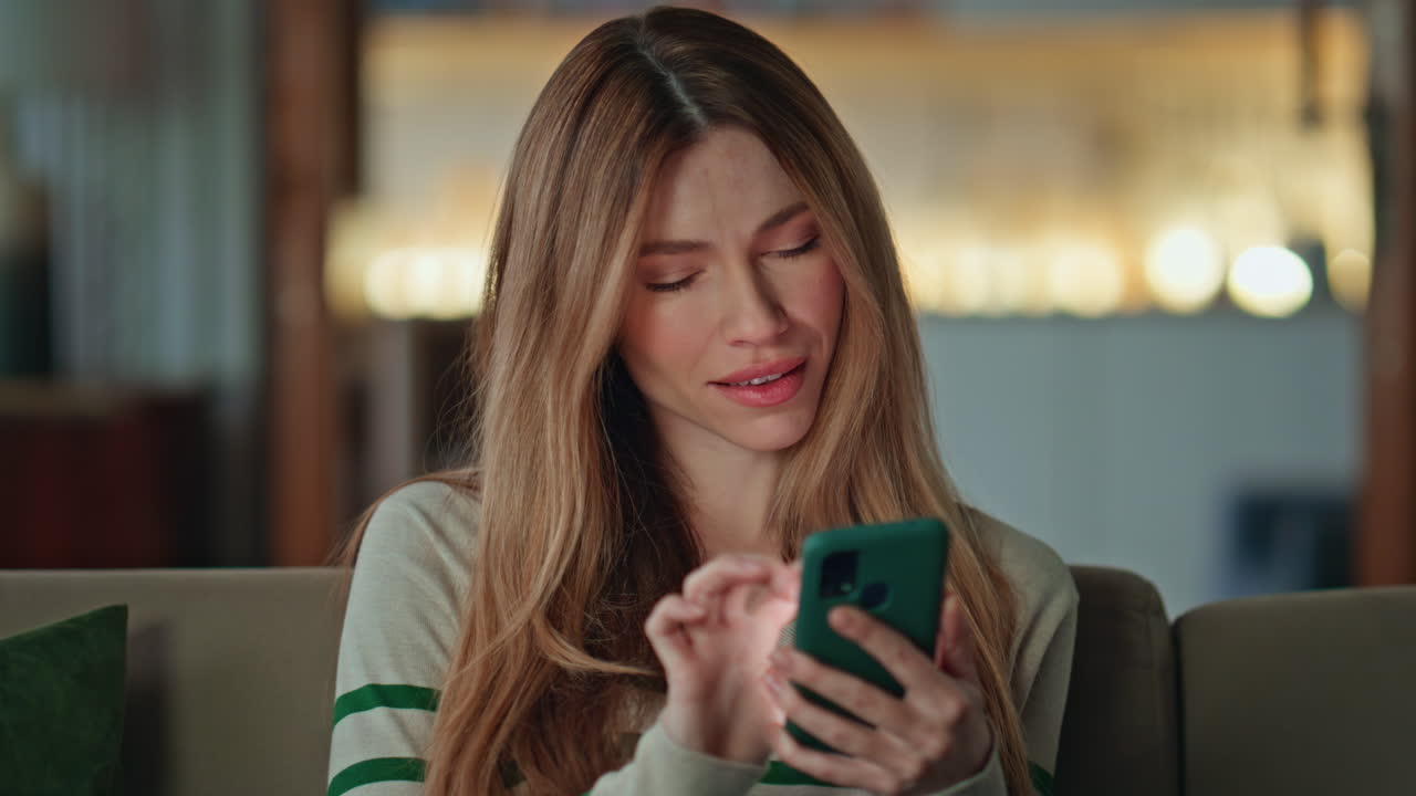 Smiling woman reading sms smartphone at couch close up. Girl choosing purchases