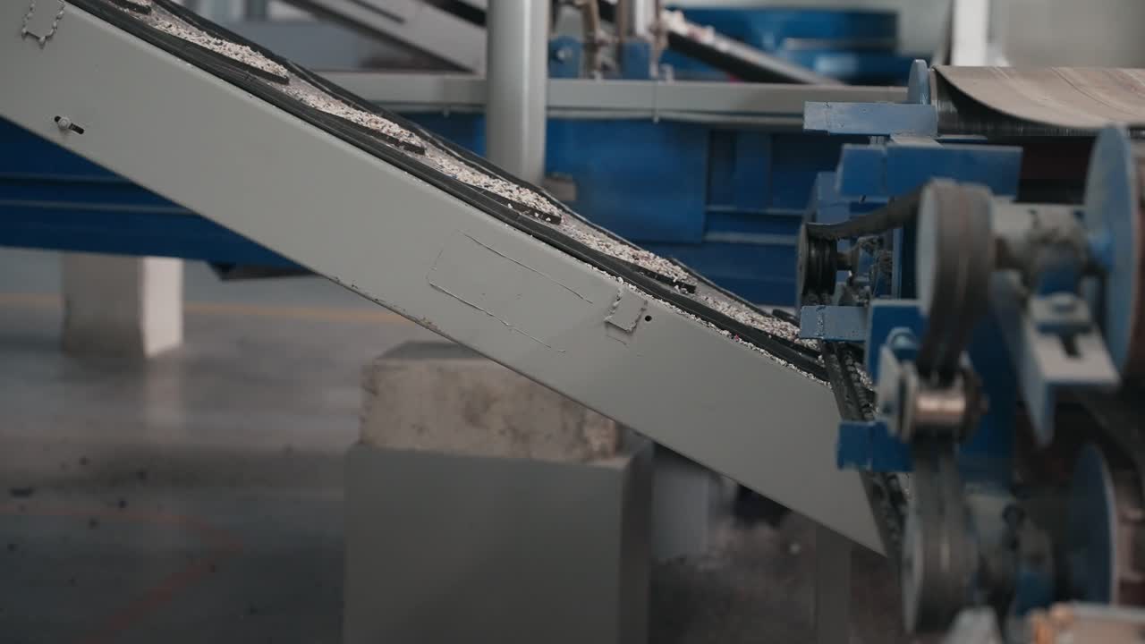 공장 내부에서 경사진 컨베이어로 운반되는 분쇄된 재료