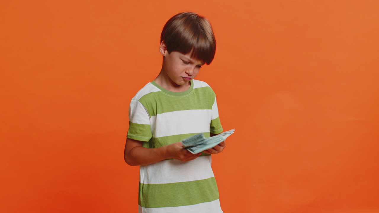 Rich happy child boy winner waving money dollar cash like a fan big income wealth success business