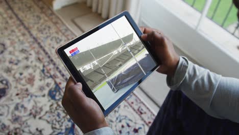 Compuesto-De-Un-Hombre-Sentado-En-Casa,-Viendo-Un-Evento-De-Salto-De-Altura-De-Atletismo-En-Una-Tableta