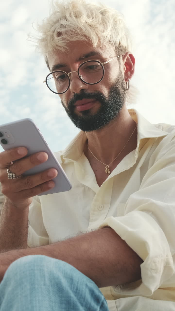 Young Man with Blonde Hair Using Smartphone Outdoors