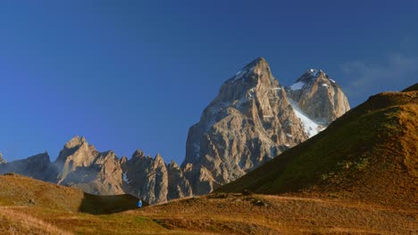 tourist in guli pass walking towards mt ushba on sunny morning, caucasus, georgia, medium