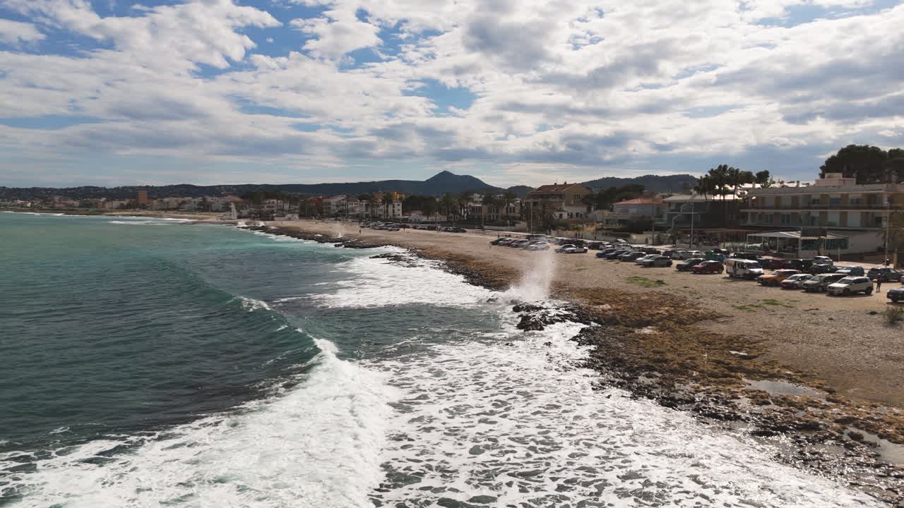 Rocky edge of Xabia coastline meets gentle waves under clear skies