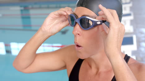 caucasian female swimmer athlete adjusts her swimming goggles