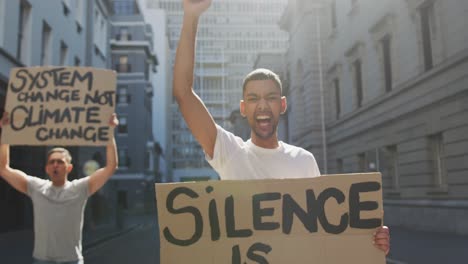 Two-mixed-race-men-on-a-protest-march-holding-placards-raising-hands-and-shouting