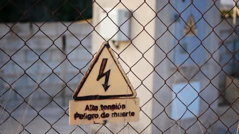 fenced off area for protection against high electric voltage shock with warning sign in spanish