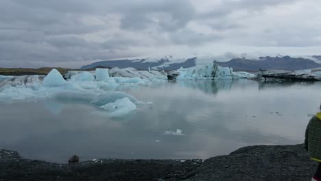 isolated and unrecognizable person walking along banks of jokulsarlon glacier lagoon, iceland