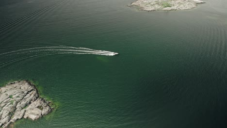Aerial,-Drone,-motorboat-driving-between-two-islands,-Finland