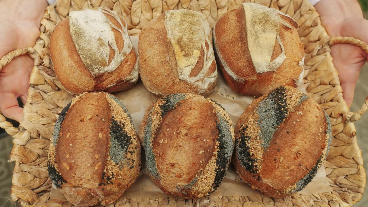 The baker holds in hands a of fresh bread with black poppy garnish on top close-up. Artisan bread is making by skill bakers using natural and high-quality ingredients. Food with health and flavour benefits.