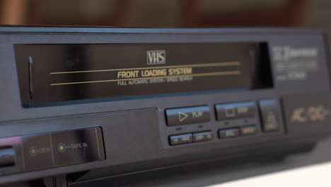insertando cinta de cassette de video vhs y presionando el botón de reproducción en el reproductor vintage de los años 80, cerca