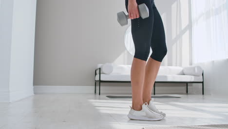 A-woman-at-home-on-a-Sunny-day-in-the-living-room-lunges-back-with-dumbbells-in-her-hands.-Healthy-lifestyle-daily-exercise-at-home.