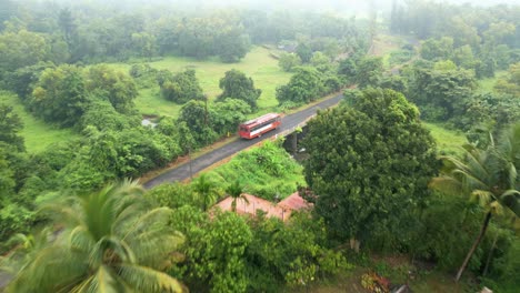temprano en la mañana el autobús rojo viaja en hermosos caminos de la aldea vista de pájaro konkan malvan
