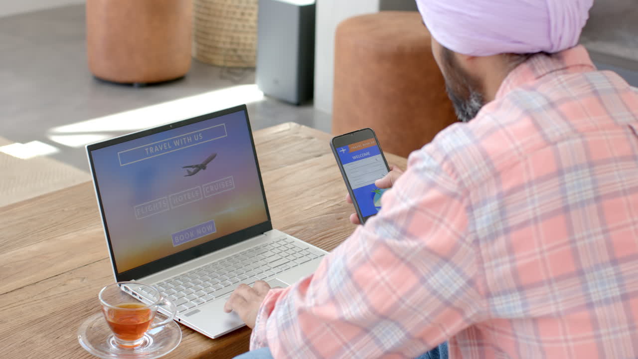 Booking travel online, man using laptop and smartphone at home with tea