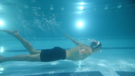 man swimming underwater in a pool
