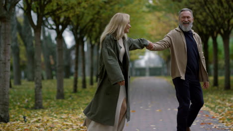 una foto amplia de una emocionante pareja romántica divirtiéndose en el parque de otoño.