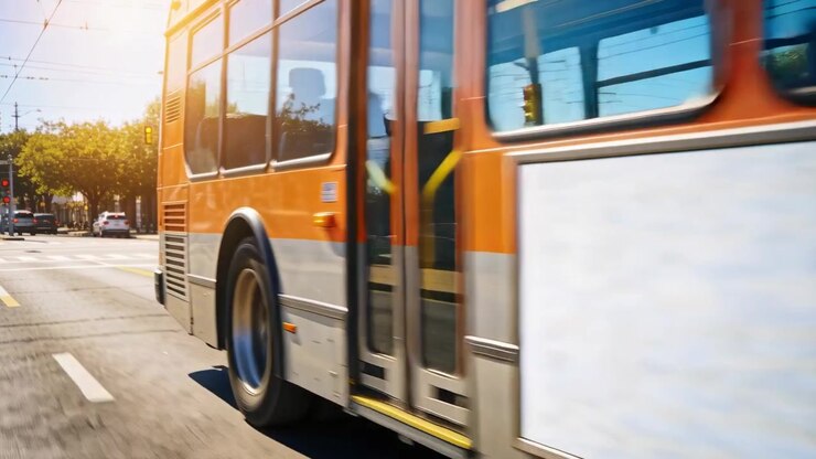 Entering from left, orange transit bus moving past crosswalk, carrying passenger wearing blue top