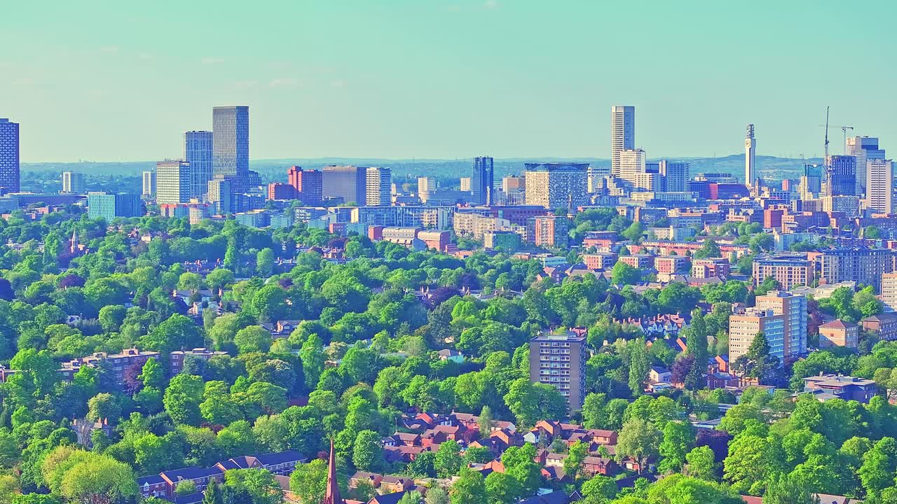 Birmingham city skyline and iconic landmarks towering over the vibrant greenery of Cannon Hill Park in summer, providing a sweeping vista of the city and its natural surroundings