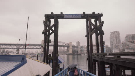 people walking towards ferry dock on granville island on cloudy day