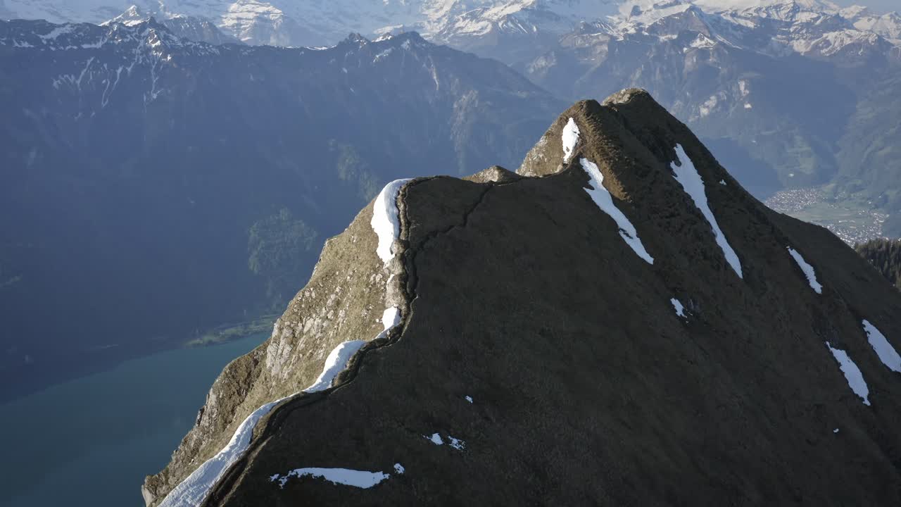 hombre caminando en la cima de una hermosa cresta entre enormes montañas y por encima de un valle verde con un lago azul