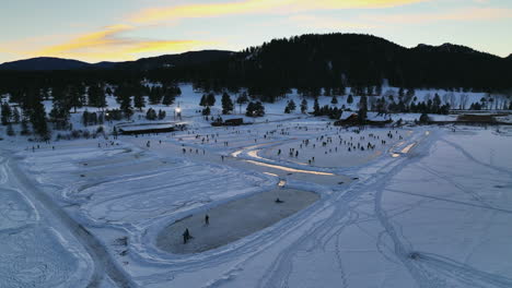 Evergreen-Lake-House-Enero-Mediados-De-Invierno-Patinaje-Sobre-Hielo,-Estanque-De-Hockey-Y-Pesca-En-Hielo-Bajo-Luces-Puesta-De-Sol-Colorado-Círculo-Cinematográfico-Derecha