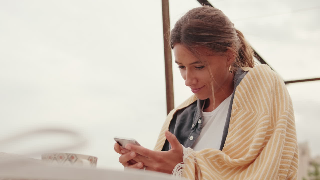 Young Woman Smiling While Using Smartphone Outdoors