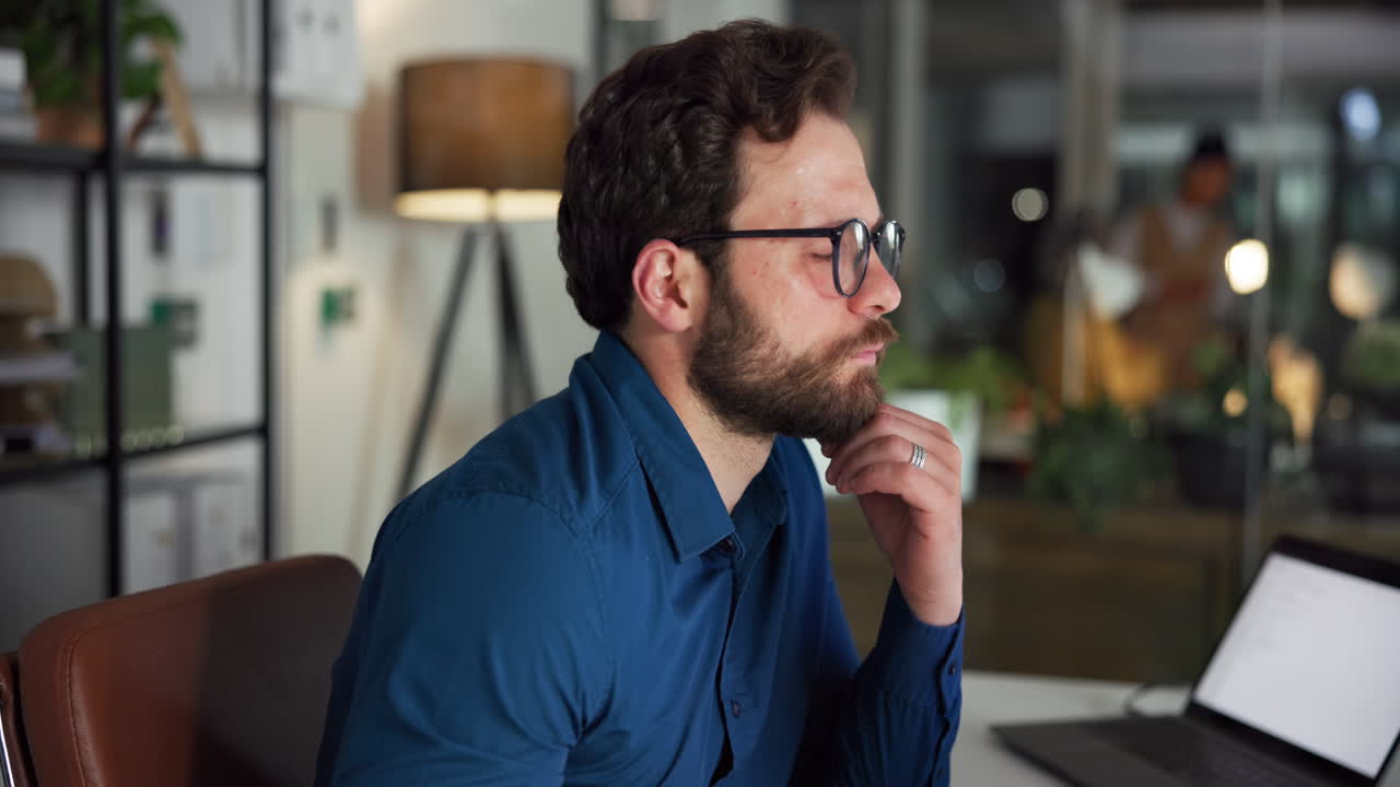 Bearded Man in Glasses Concentrating on Laptop in Office