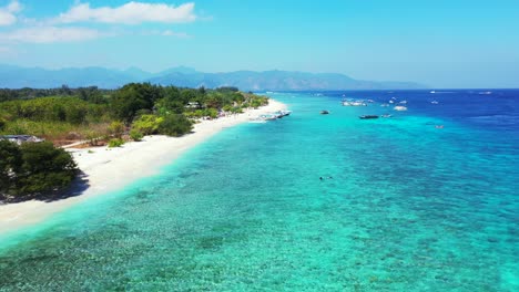 Quiet-exotic-beach-around-green-tropical-island,-washed-by-clear-crystal-water-of-blue-turquoise-sea-full-of-boats-under-bright-sky-in-Bali