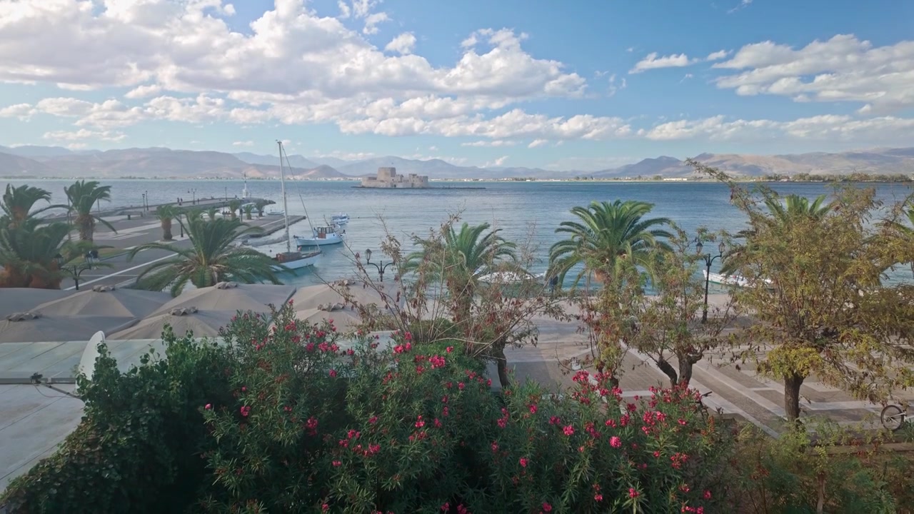 Nafplion Bouritz koyu sahil gezinti yolundaki palmiye ağaçları üzerinden manzaralı bir görünüm.