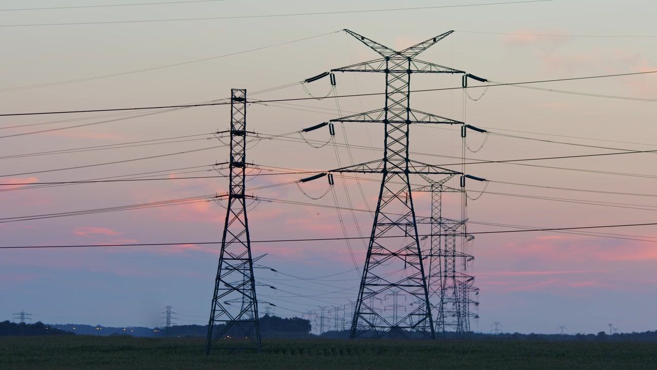 Transmission towers with power lines in blue evening light