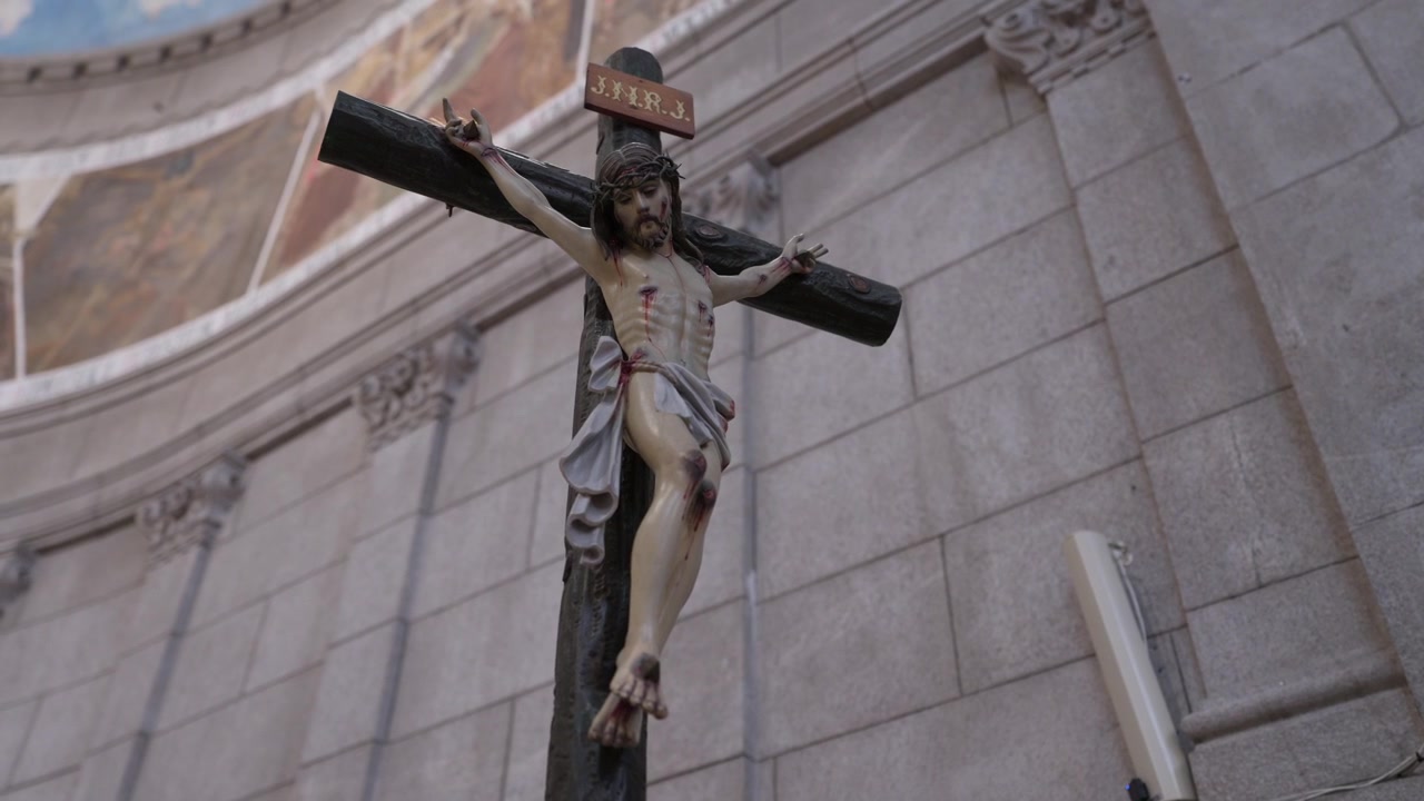 Crucifixo esculpido com figura de Cristo e placa INRI contra parede de granito dentro de uma igreja