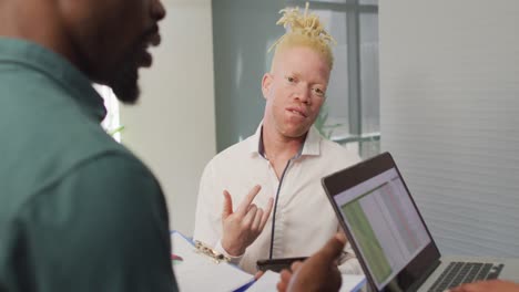 diverse business people discussing with laptop and documents in creative office