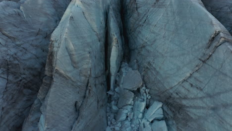 Extremely-close-aerial-of-glacier-ice-revealing-landscape-and-mountains-in-distance