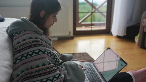 una mujer trabajando en una computadora portátil en un ambiente casero acogedor.
