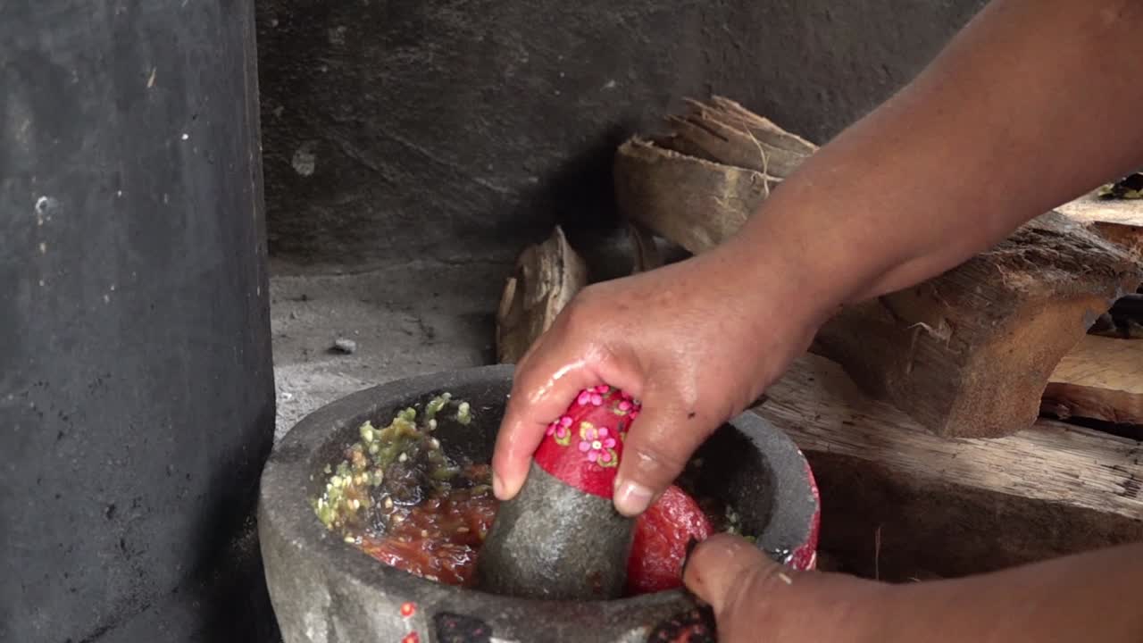 Una donna che prepara salsa messicana rossa su un molcajete