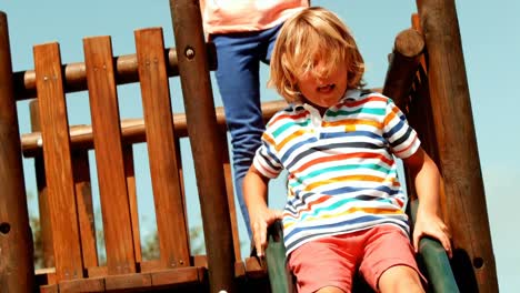 schoolboy enjoying while playing on slide