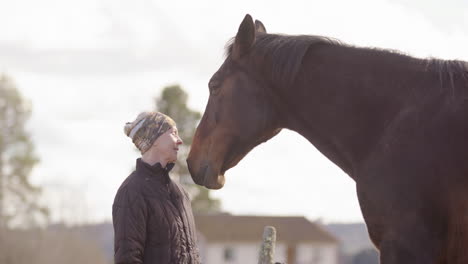 emotional woman in front of big empathetic horse starts crying, equine therapy