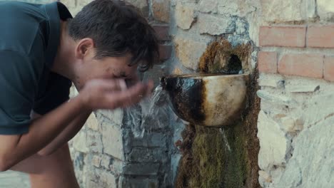 Joven-Refrescándose-En-Una-Fuente-Pública-Durante-Una-Ola-De-Calor