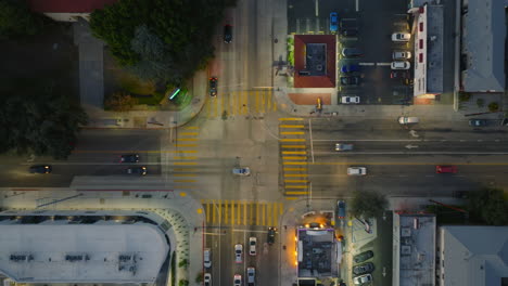 intersección concurrida vista desde arriba, toma aérea de vehículos no tripulados moviéndose a través de la intersección en las primeras horas de la noche